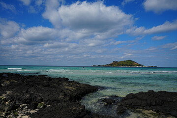rock beach and island against charming clouds