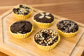 Mini tart with brownie filling. Crispy on the outside, soft on the inside, combined with various toppings such as peanuts, choco chips, cheese and almonds. Perfect for serving with coffee and tea