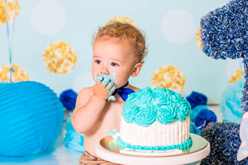 Baby boy playing with a cake during cake smash birthday party