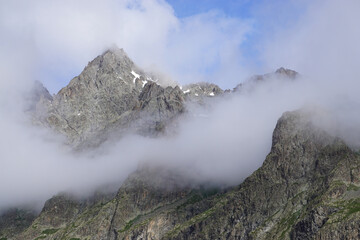 landscape with fog lifting by the snowy peak in the southern Alps, France