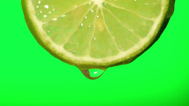 Macro image of water droplets falling from lemon slices on green background.
