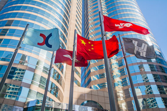 The flags hoisting at the Forum of Exchange Square with skyscrapers in the background. Flags of HKSAR, China,  Hongkong Land and Hong Kong Stock Exchange (HKEx) in CENTRAL, HONG KONG on DEC 21, 2017