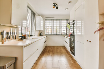 a kitchen with white cabinets and wood flooring in the middle of the room, looking towards the dining area - obrazy, fototapety, plakaty