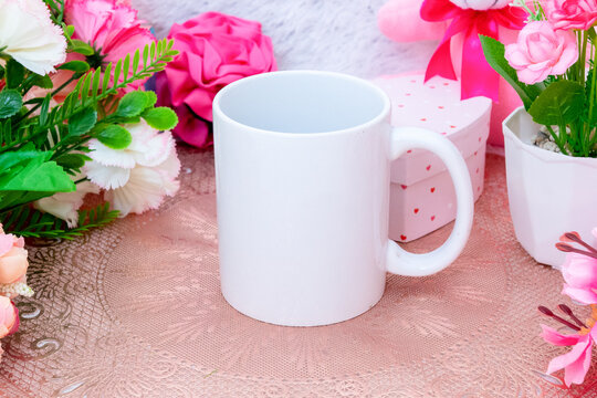 White blank coffee mug on the top of a small rounded table cloth surrounded by valentine themed decorations