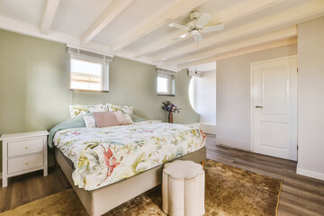 a bedroom with a bed, dresser and ceiling fan in the photo is taken from the front end of the room