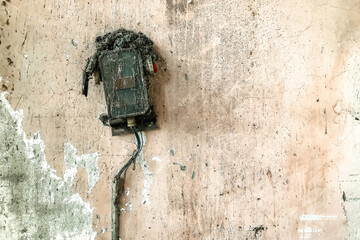 Fototapeta na wymiar Background of electricity meter on ruined filthy wall. Abandoned rusty electric power distribution box on dirty textures wall in industry building. Concept of old equipment. Copy text space