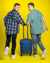 guys with a suitcase. Studio colored background. blue yellow. Cheerful boys, students gathered for study or vacation. teenager laughs.