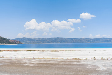 Fototapeta na wymiar The turquoise waters of Salda Lake, the white mineral-rich beach and the blue sky. Salda Lake is a turquoise crater lake. Salda Lake, Burdur, Turkey