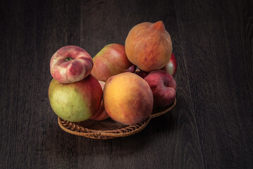 Still life of fresh peaches and apples on a dark background.