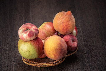 Still life of fresh peaches and apples on a dark background.