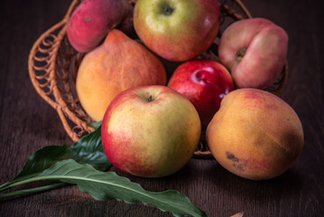 Naklejka na ściany i meble Still life of fresh peaches and apples on a dark background.