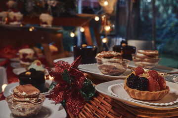 Mesa de postres. Peque&ntilde;a tarta de frutos rojos sobre canasta con fondo de luces y adornos navide&ntilde;os