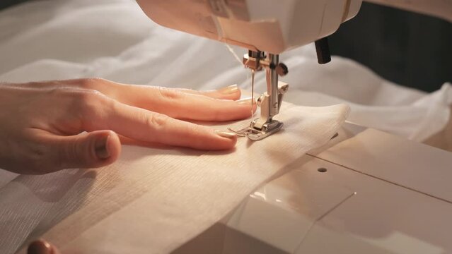 Close-up shot of sewing machine sews a line, a seamstress woman cuts off a thread