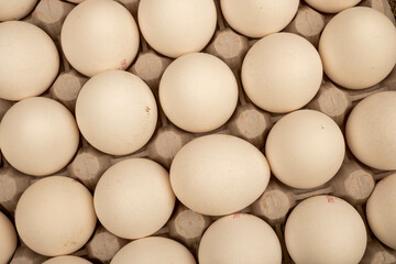 White chicken eggs in a cardboard box on the table. Close-up, selective focus