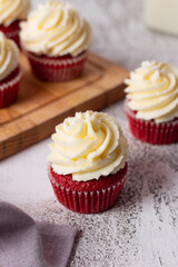 Red velvet cupcakes with cream cheese on wood board