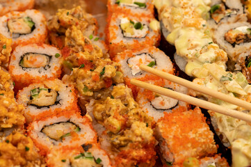 A set of different types of rolls in a box. Top view of various portions of vegetarian and fish rolls.