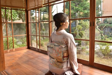 古民家の縁側に座る着物を着た若い女性の後ろ姿
