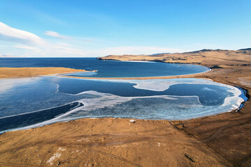 Winter landscape, aerial view. Frozen Lake Khankhoy on the island of Olkhon and unfrozen Lake Baikal in December.