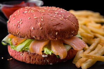 Red burger with salmon, lettuce and cucumber