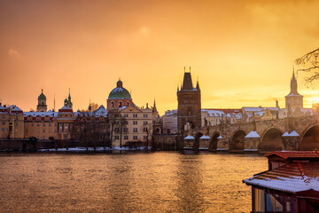 Naklejka premium Beautiful winter sunrise view of the skyline of Prague with Charles Bridge and the snow covered old town roofs, Czezch republic 