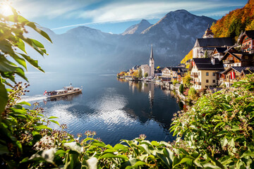 Beautiful sunny landscape of Hallstatt mountain village with Hallstatter lake and boat in Austrian Alps. Austria, Salzkammergut. Concept ideal resting place. Popular travel destination. postcard