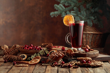 Hot Christmas drink with spices and fruits on an old wooden table.