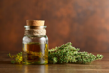 Bottle of thyme essential oil with fresh thyme.
