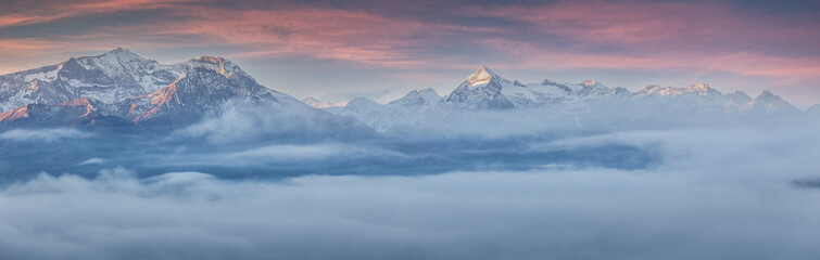 Scenic foggy landscape during sunset. Fantastic morming panorama of mountains. Impressive nature scenery in alps. Atmospheric colorful  landscape with misty lake and rocky mount on background.