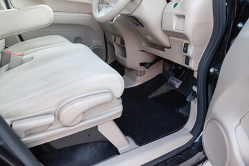Clean car floor mats of black carpet under front driver seat in the workshop for the detailing vehicle before dry cleaning. Auto service industry. Interior of sedan.