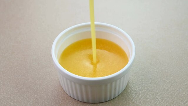 Pouring ghee in a white bowl