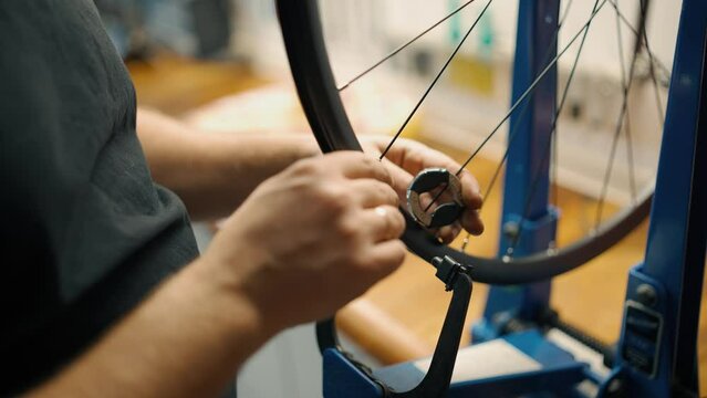 A bicycle mechanic fixes and adjusts the spoke tension on cycle bike wheel in a repair shop