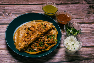 Gringa, typical Mexican dish. Gringa pastor a la diabla served with sauces and other condiments on a wooden table.