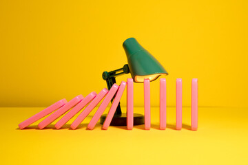 Green toy lamp stoping domino effect of pink domino