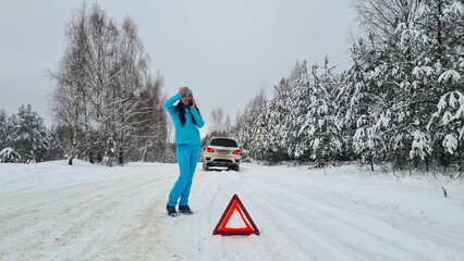 Woman calling emergency service on highway in winter with broken car