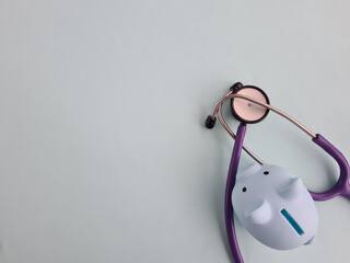 Piggy bank with stethoscope on blue background
