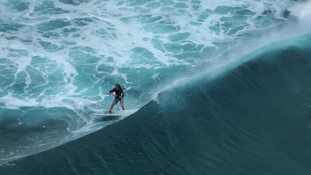 An athlete on a wave board rides the big ocean waves of a living reef in the Indian Ocean. One of the best surf spots on the planet. Sports hobby