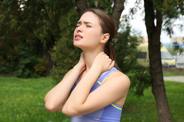 Naklejka na ściany i meble Young woman suffering from neck pain outdoors