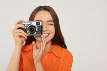 Young woman with camera taking photo on white background, space for text. Interesting hobby