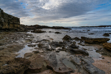 rocky cove and sandy beach under an expressive sky on the rugged west coast of Sardinia