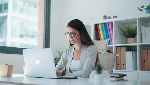 Video of concentrated business woman working with laptop at the office.