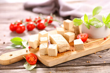 tofu cube and tomato on wooden board