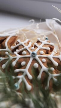 Christmas gingerbread cookies lie in a white box with straw near a pine branch. Christmas cookies with icing. cookie in the form of a snowflake with blue dots. gingerbread lies on a white table.