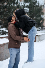 Fototapeta na wymiar Outdoors Valentines Day Date Ideas for Couples. Winter love story. Cold season dating for couples. Young couple in love kissing in winter city street park