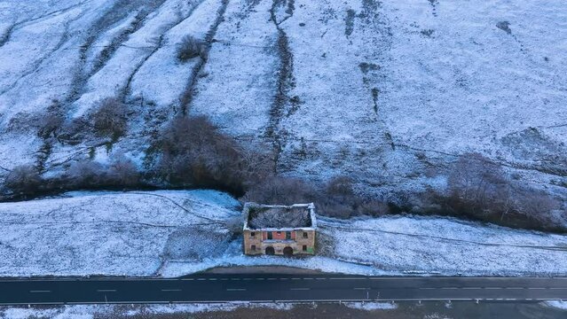 Abandoned house and snowy landscape of cabins and meadows in Puerto de los Tornos, between Cantabria and Burgos. Aerial view from a drone. Castile and Leon, Spain, Europe