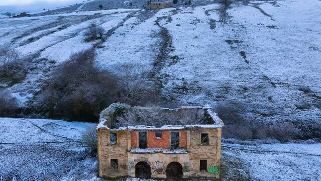 Abandoned house and snowy landscape of cabins and meadows in Puerto de los Tornos, between Cantabria and Burgos. Aerial view from a drone. Castile and Leon, Spain, Europe