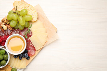 Snack set with delicious Parmesan cheese on light wooden table, top view. Space for text