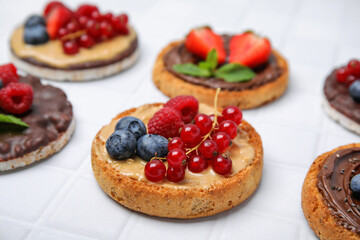 Fresh rice cakes and rusks with different toppings on white table, closeup