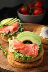 organic rusks with salmon, cream cheese and avocado served on wooden board, closeup