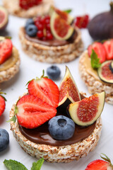 Tasty crispbreads with chocolate, figs and berries on light table, closeup