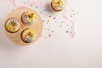 Dessert stand with cute sweet unicorn cupcakes on white table, flat lay. Space for text © New Africa